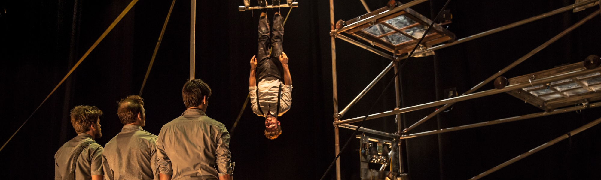 person suspended upside down on a scaffolding frame with 3 bystanders looking on person suspended upside down on a scaffolding frame with 3 bystanders looking on
